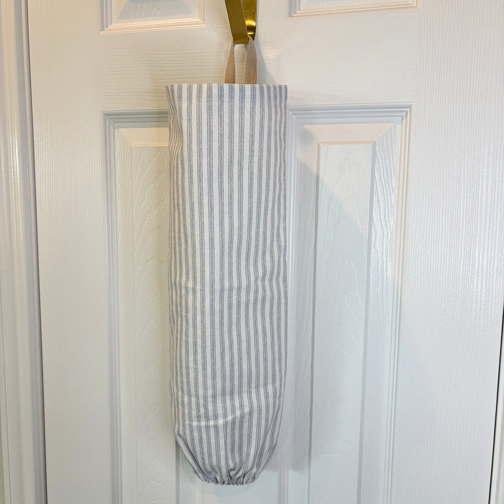 White and Blue striped Plastic Bag Organizer with tan loop hanging on a gold hook against a white door