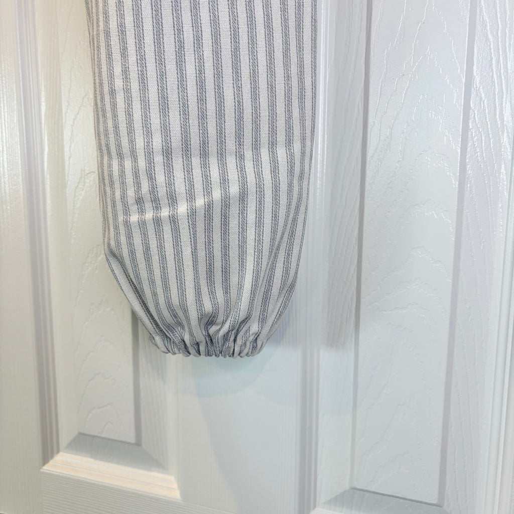 close up scrunched bottom of White and Blue striped Plastic Bag Organizer against a white door
