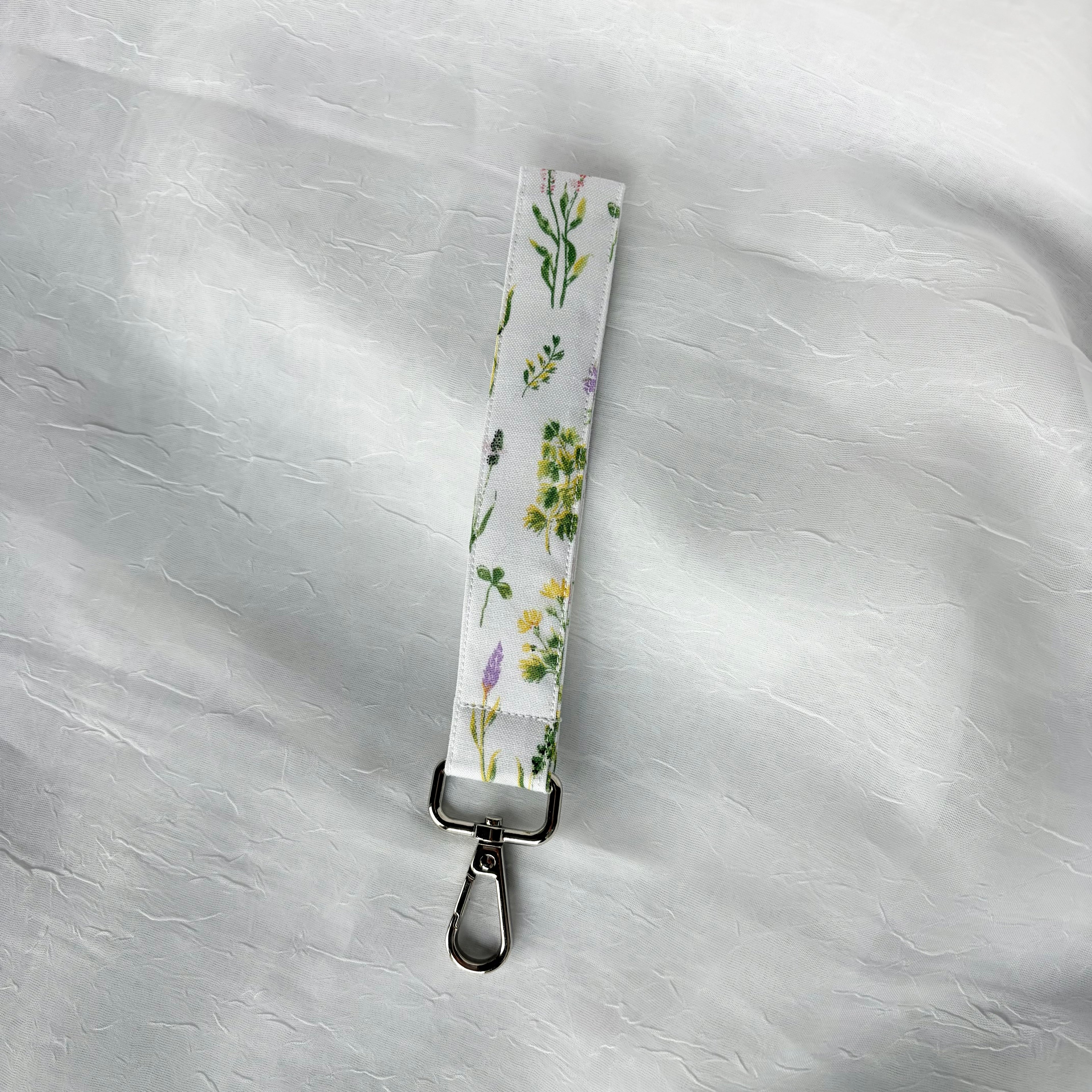 wild flowers  in pink purple and yellow with green stems and leaves organized in vertical lines on white fabric keychain wristlet with silver lobster clip