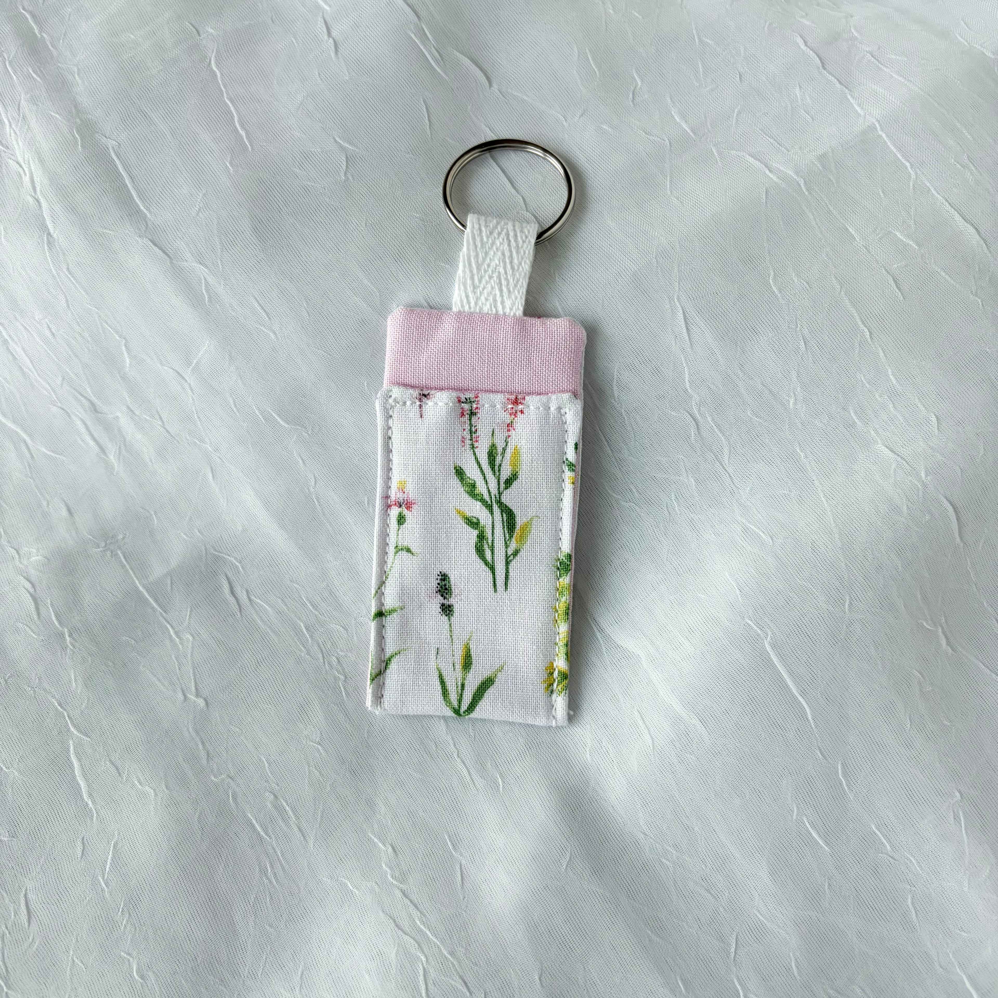 Floral with pink accent chapstick holder with keychain ring on a textured white background