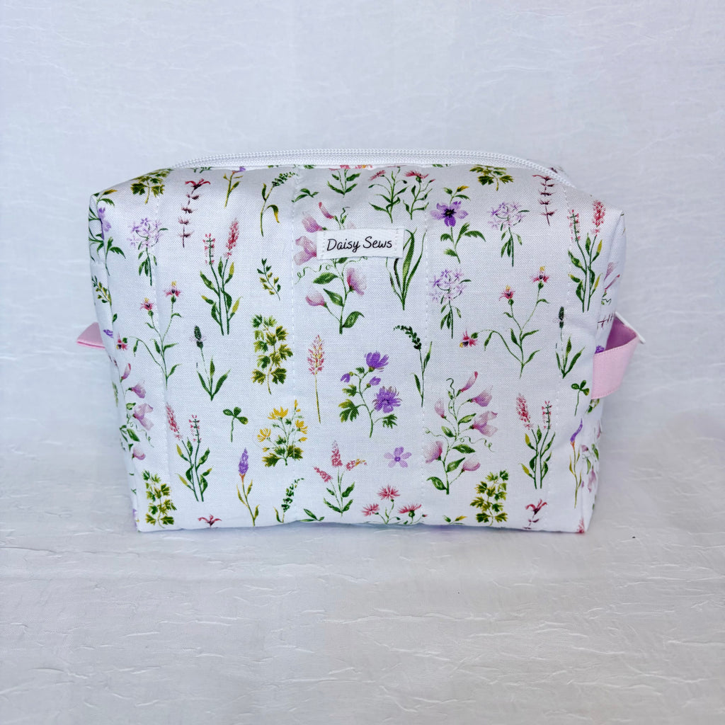 Floral-patterned fabric bag with 'Daisy Sews' branding on a light gray background