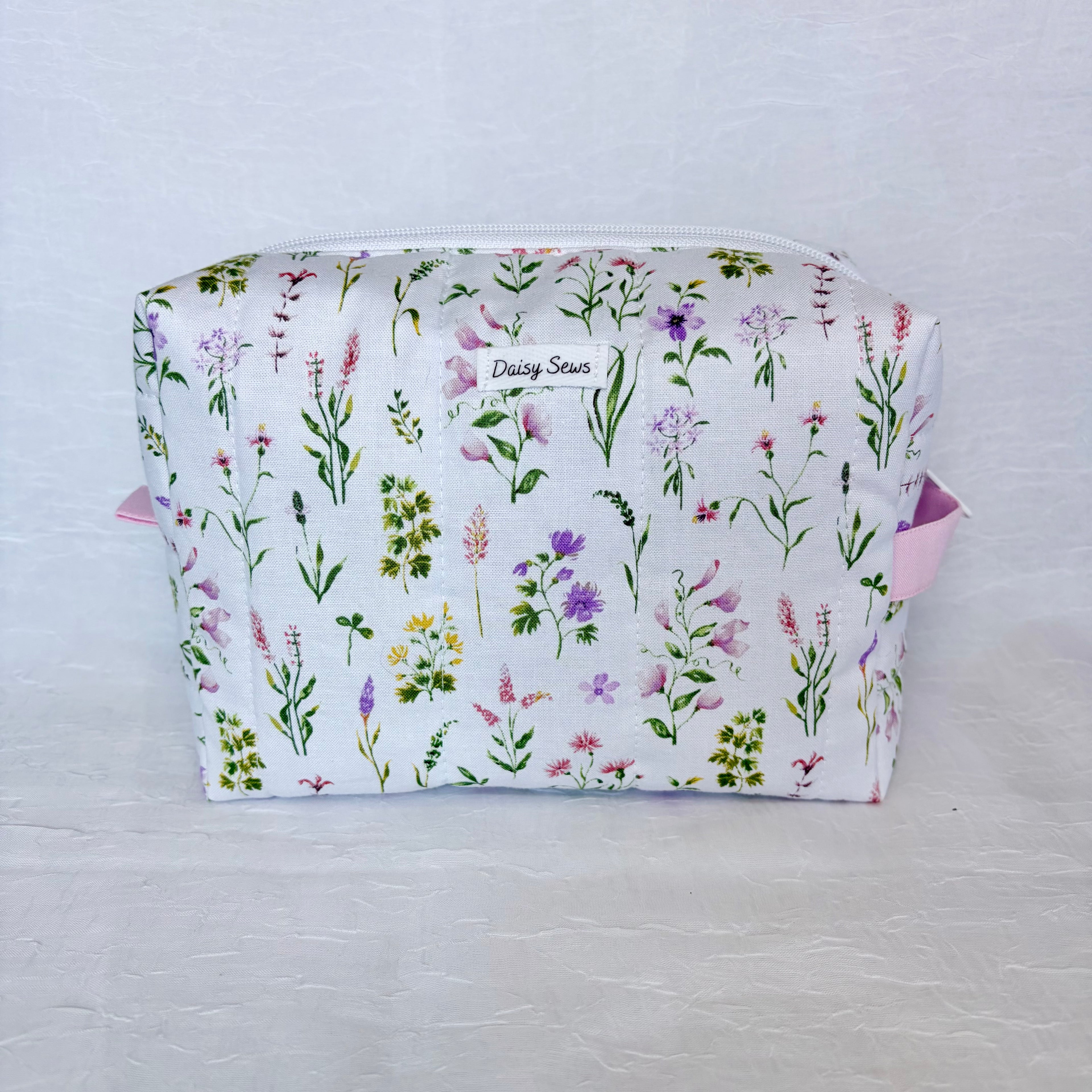 Floral-patterned fabric bag with 'Daisy Sews' branding on a light gray background