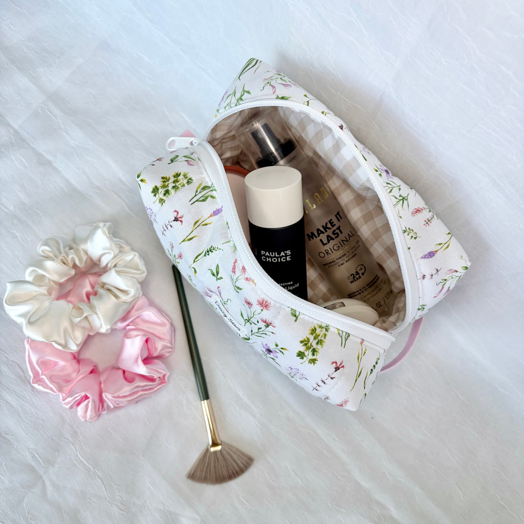 Floral makeup bag with beauty products and accessories on a white surface