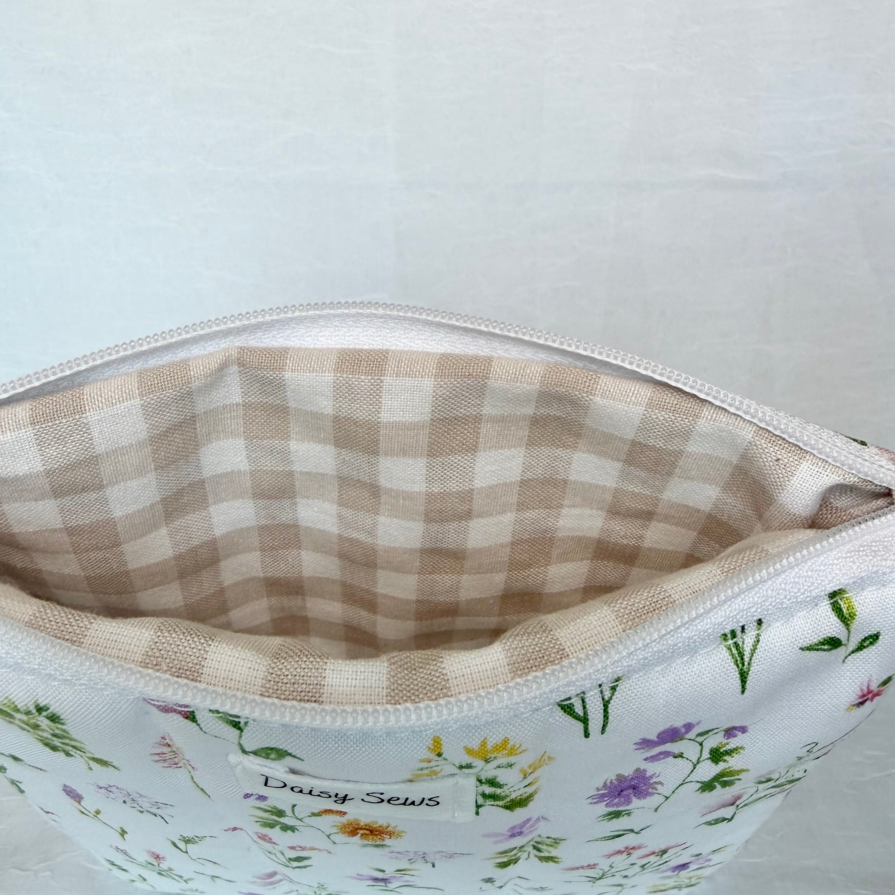 Floral-patterned pouch with a beige checkered interior on a light gray background