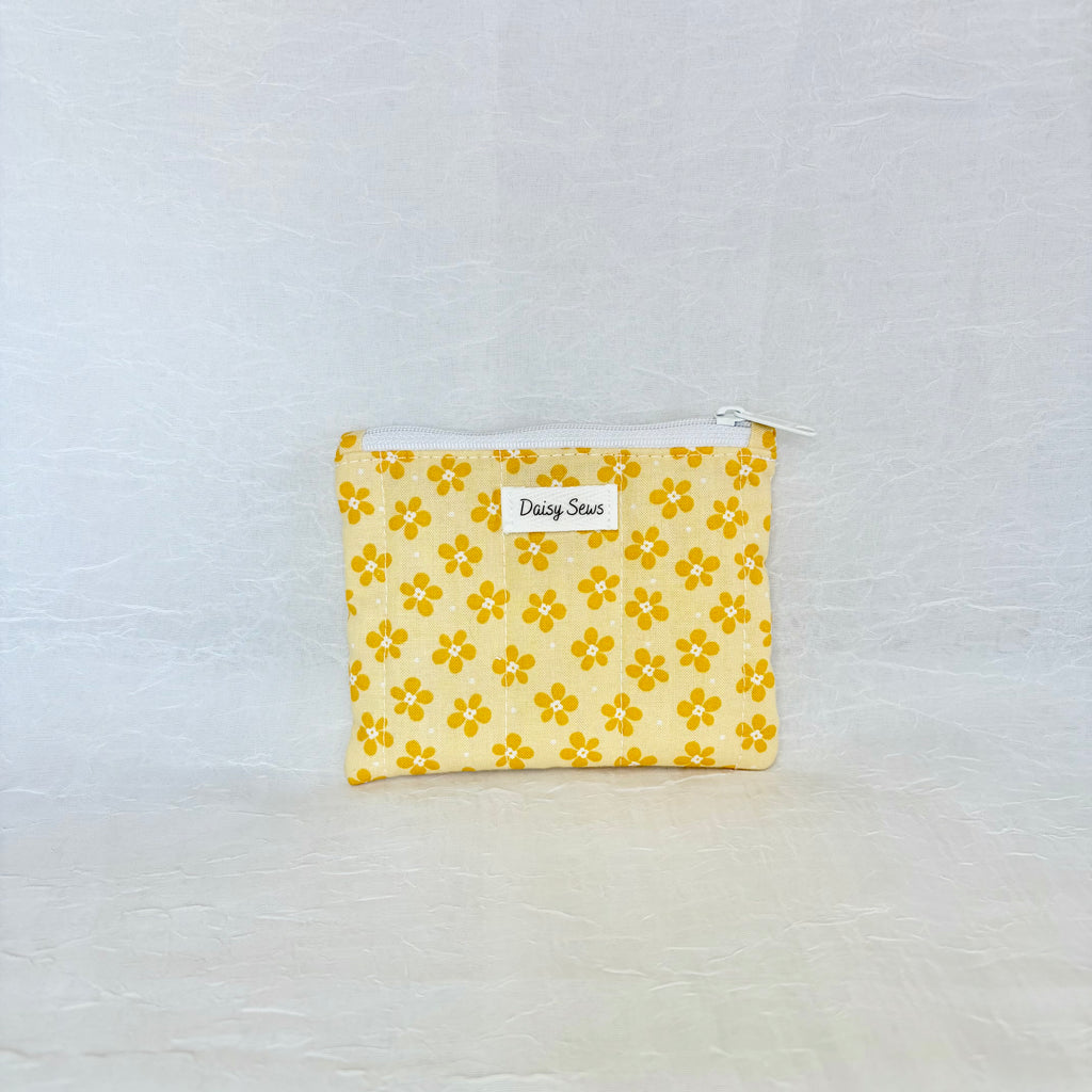 Yellow floral pouch with a white zipper on a light gray background