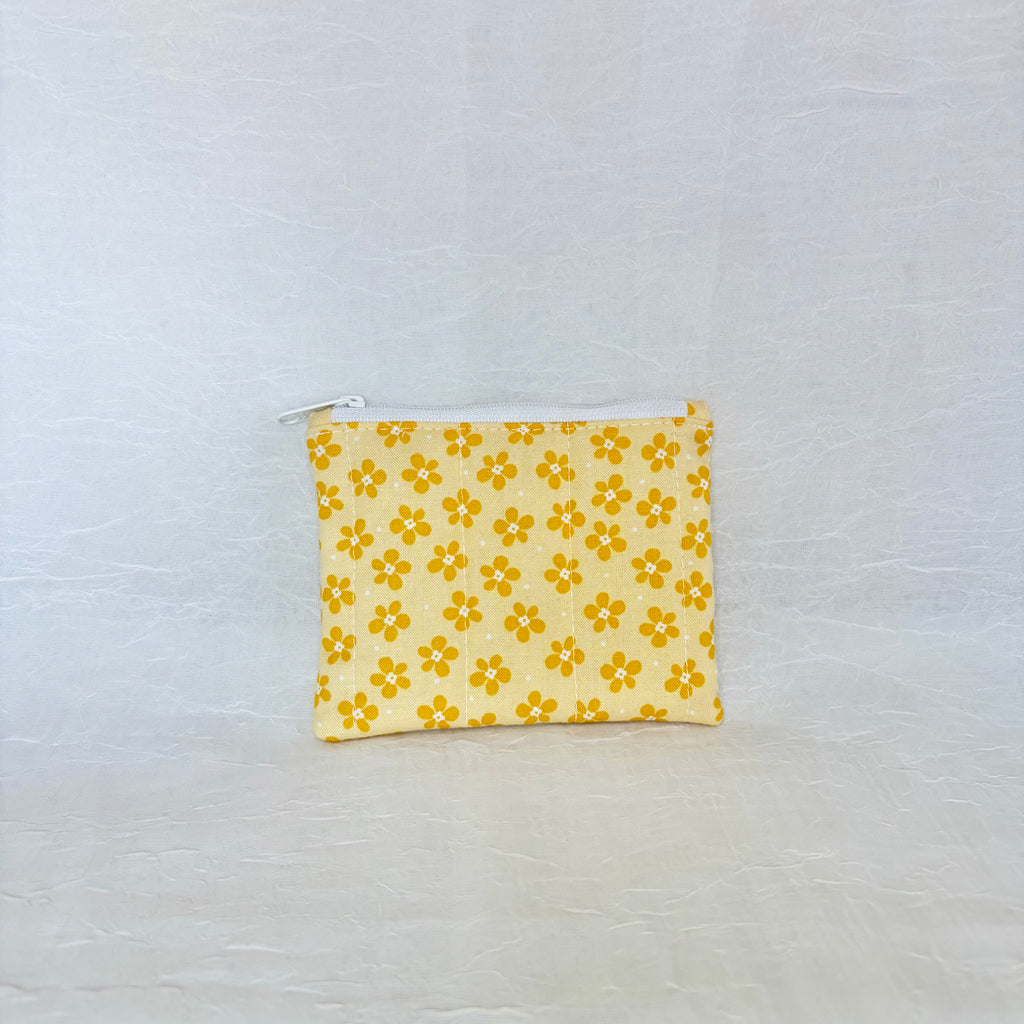 Yellow floral-patterned pouch on a light gray background