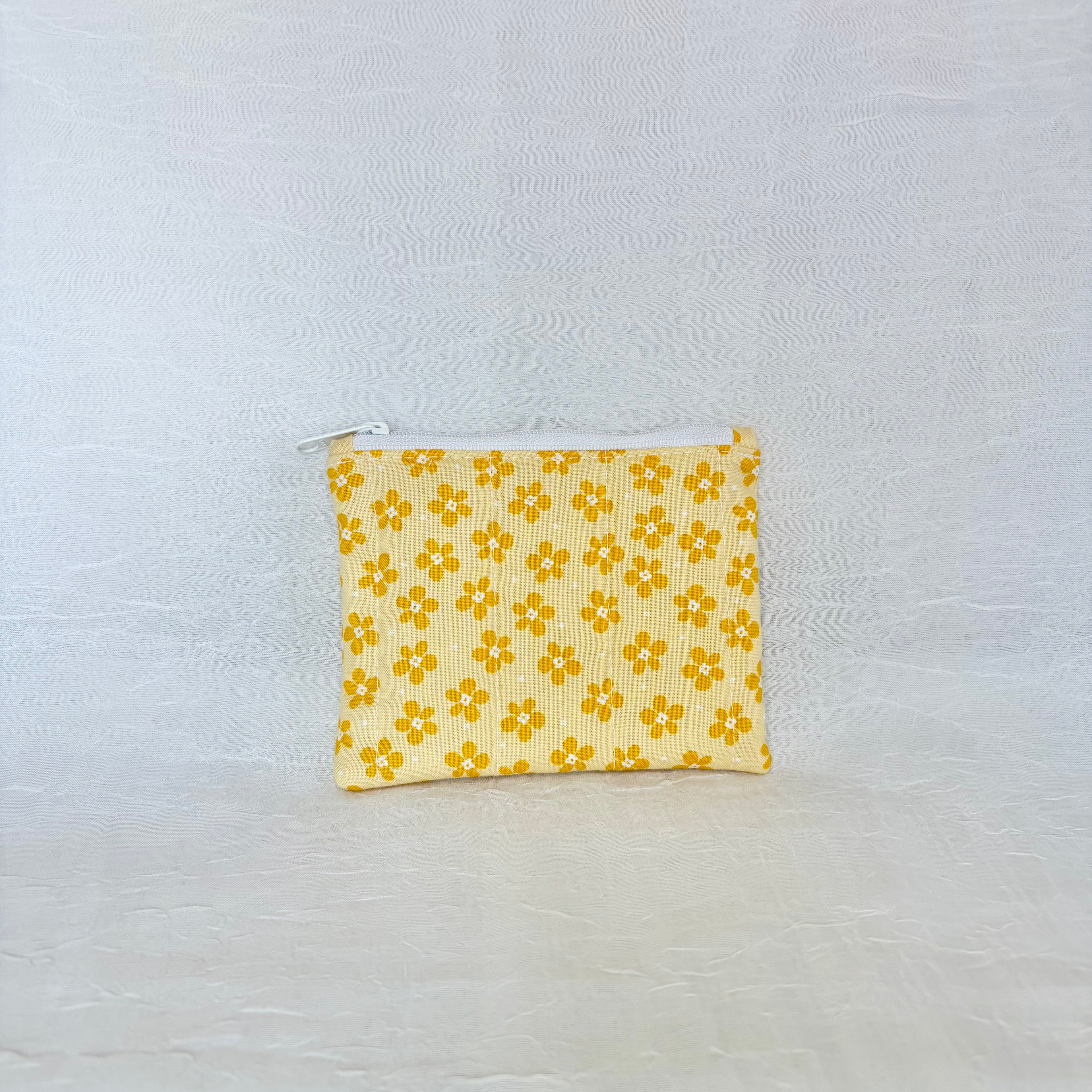 Yellow floral-patterned pouch on a light gray background