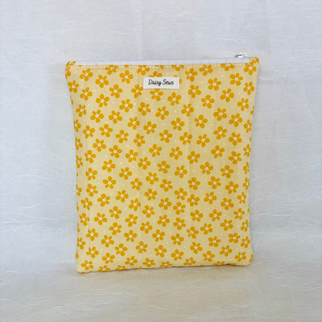 Yellow floral patterned pouch with a white zipper on a light gray background