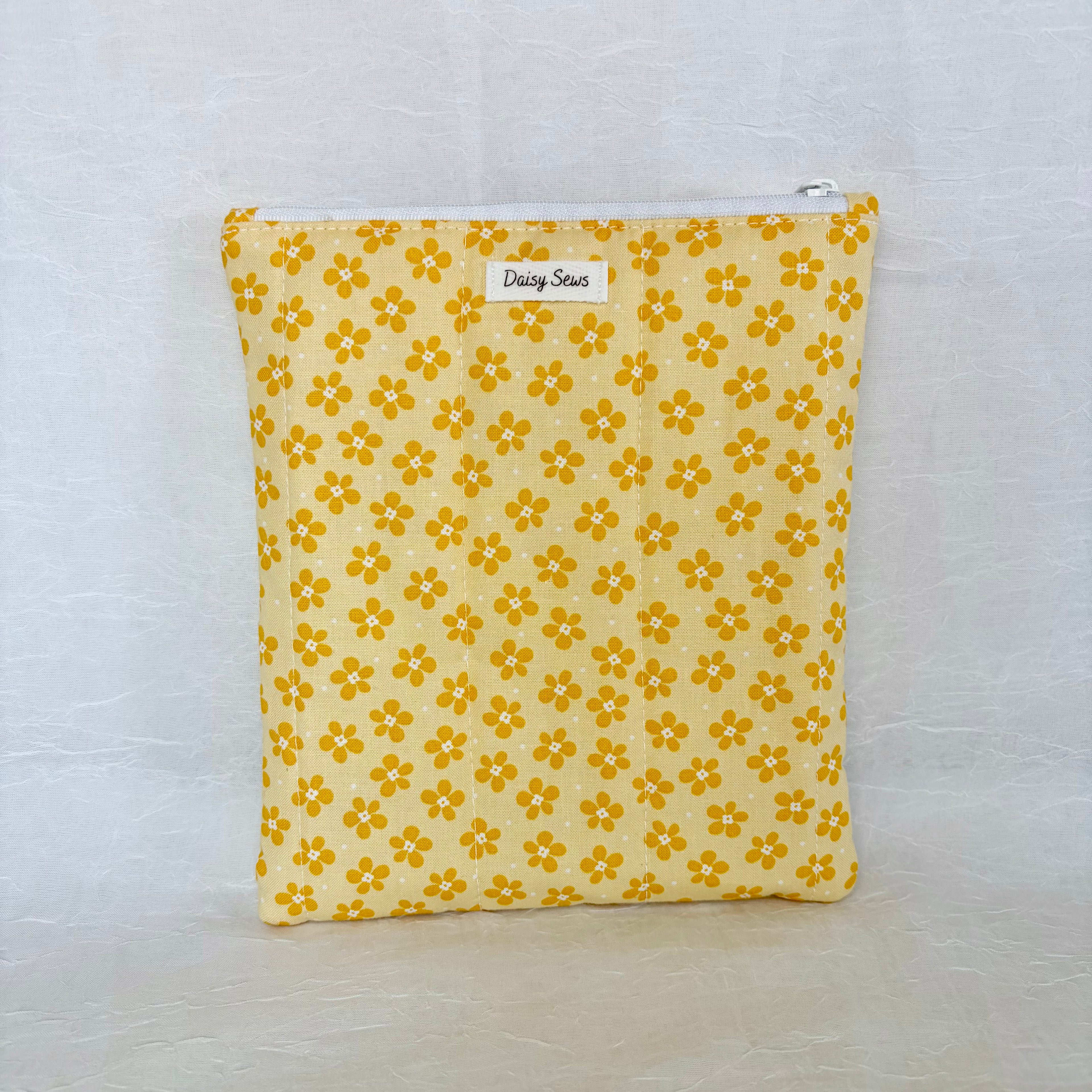 Yellow floral patterned pouch with a white zipper on a light gray background