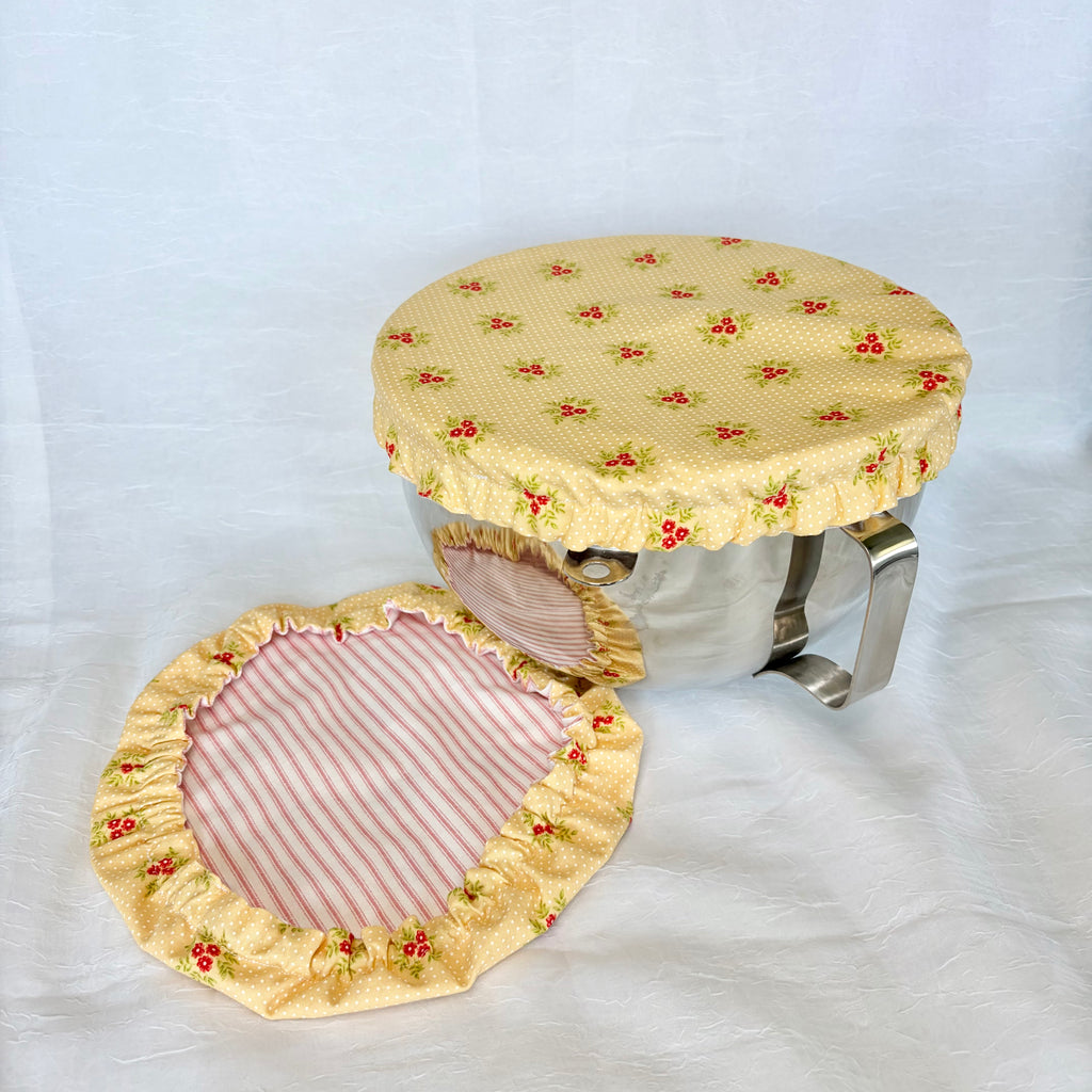 yellow & pink floral bowl cover on silver bowl with white background with 2nd cover on surface