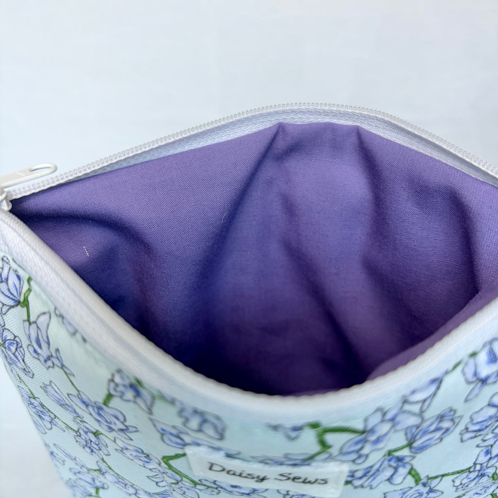Close-up of a floral-patterned bag with a purple interior on a white background